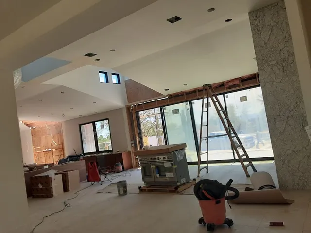 Large living area with ladder and floor protection during interior painting prep in Phoenix